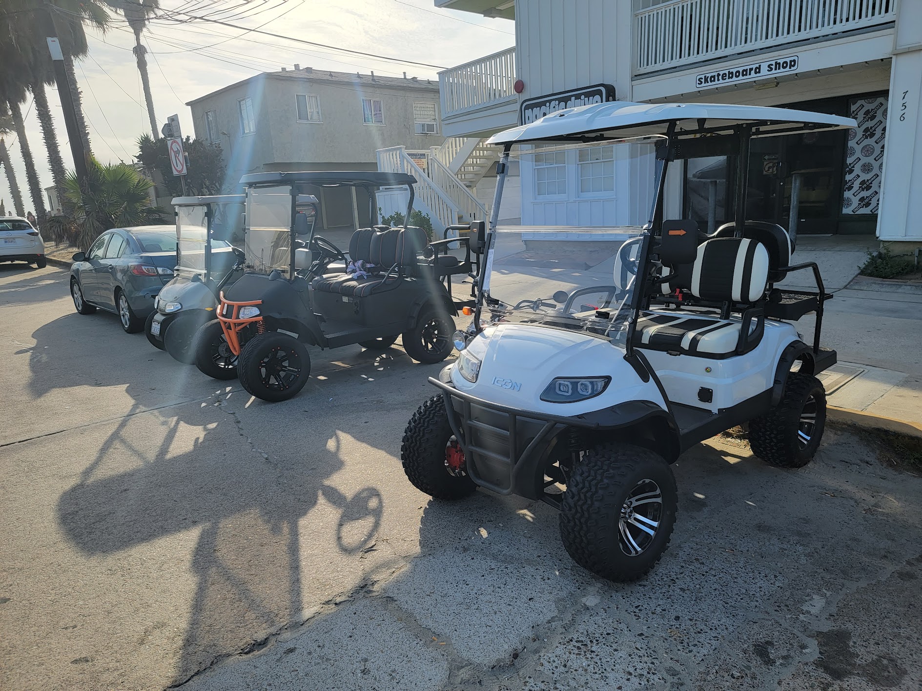 Golf carts parked near a beach-adjacent commercial building.
