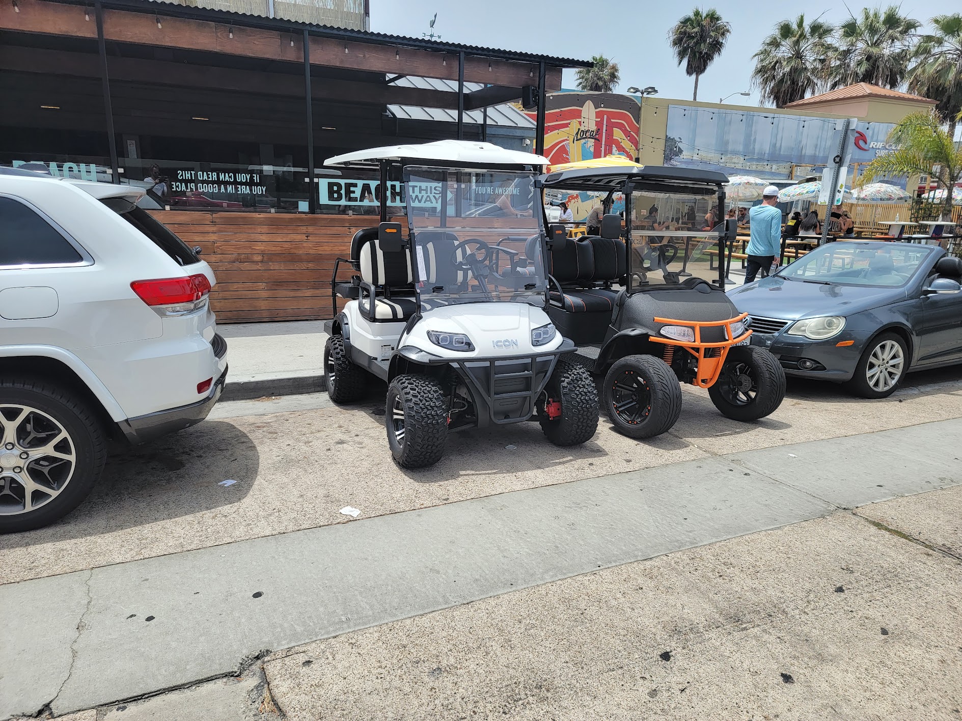 Golf carts using curb parking in a busy pedestrian area.